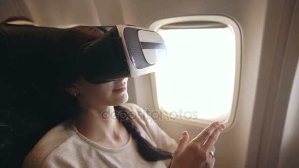 若い観光客女性リラックスし、飛行機の飛行中にスマート フォンの Vr のヘッドセットを使用 — ストック動画