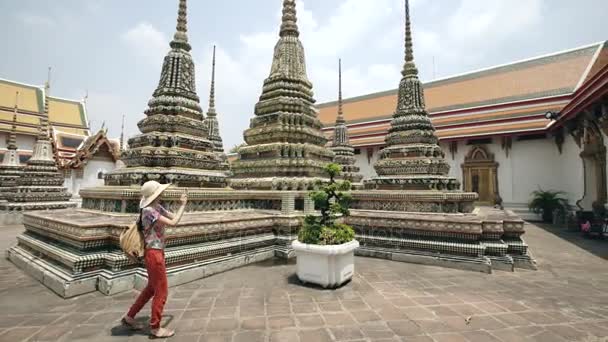 Jonge vrouw toeristische fotograferen met smartphone op sightseeing van de tempel in Bagnkok Thailand tijdens reizen — Stockvideo