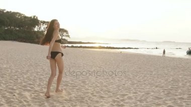 Ağır çekim genç seksi kız bikinili çalıştıran ve adam sahilde günbatımı içinde arama