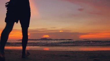 Mutlu sevgi dolu çift silüeti ağır çekim karşılamak ve kumsala günbatımı üzerinde okyanus kıyısında gidelim.