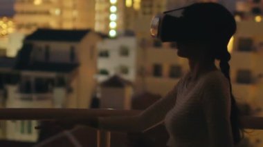 Sanal gerçeklik kulaklık kullanarak ve geceleri Vr deneyimi olan çatı katı terasında genç kadının ağır çekim