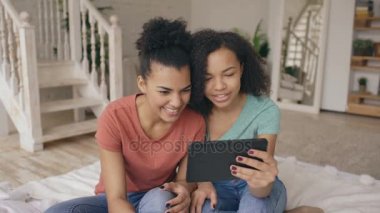 Neşeli karışık yarış genç komik kız arkadaşlarıyla birlikte evde tablet bilgisayarda skype konuşurken