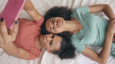 Neşeli karışık yarış komik kız yatak odası evde yatakta selfie portre yapma Üstten Görünüm