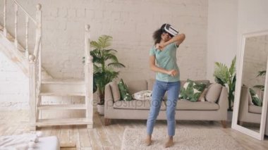 Mutlu gülümseyen genç karışık yarış kız VR kulaklık gözlükle sanal gerçeklik ve evde dans deneyim elde
