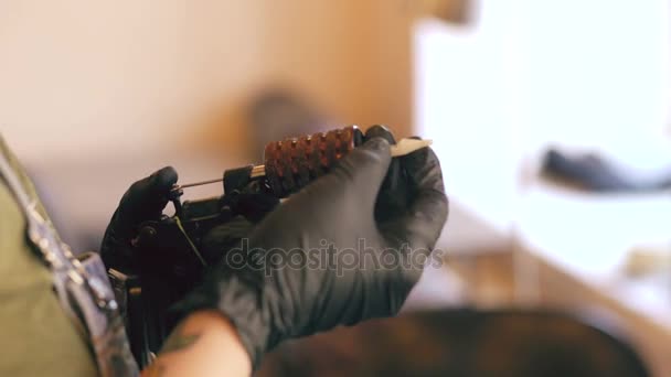Detailní záběr na tetování umělec žena nastaví stroj pro tetování ve studiu doma