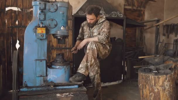 Bärtiger junger Mann Schmied mit hydraulischer Presse zur Herstellung von Stahlwaffen in der Schmiedewerkstatt — Stockvideo