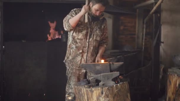 Skäggig ung man smeden manuellt smide Het metall på städet i smedjan med spark fyrverkerier — Stockvideo