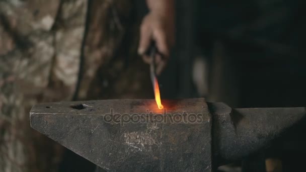 Close-up van bebaarde jongeman smid handmatig het smeden van ruwijzer op het aambeeld in smithy met vonk vuurwerk — Stockvideo