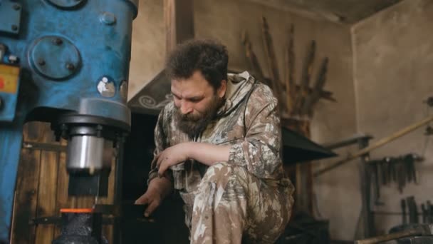 Ferreiro jovem barbudo usando prensa industrial para fabricação de armas de aço na oficina de ferreiro — Vídeo de Stock