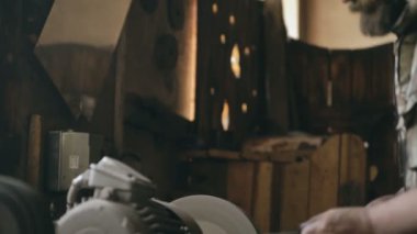 Sakallı genç adam demirci el ile metal bıçak Bileme Makinası geleneksel smithy üzerinde Lehçe
