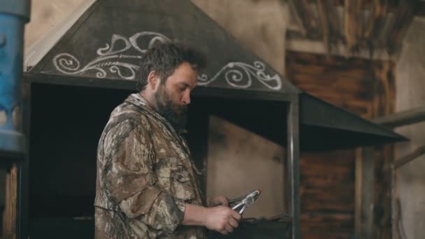 Bearded pandai besi lentur pisau logam panas dengan tang dan palu tradisional smithy — Stok Video