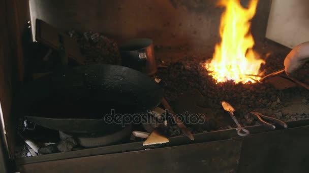 Closeup smid handmatig temperen stalen mes in koude olie in de buurt van open haard in traditionele smithy — Stockvideo