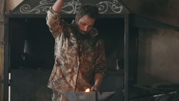Slowmotion av skäggig ung man smeden manuellt smide Het metall på städet i smedjan med spark fyrverkerier — Stockvideo