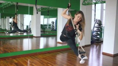 Trx üzerinde çalışan ve spor salonunda fitness askıları silahlarla eğitim salonunda genç çekici kadın