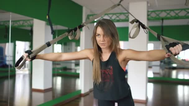 Trx üzerinde çalışan ve spor salonunda fitness askıları silahlarla eğitim salonunda genç kadın — Stok video