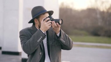 Şık genç fotoğrafçı adam açık havada duran ve turistik Gezilebilecek Yerler seyahat sırasında fotoğrafını şapkalı