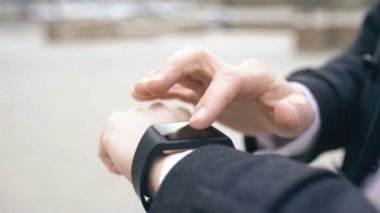 Onun smartwatch dokunmatik ekran ayakta sokakta kullanarak iş adamı ele closeup