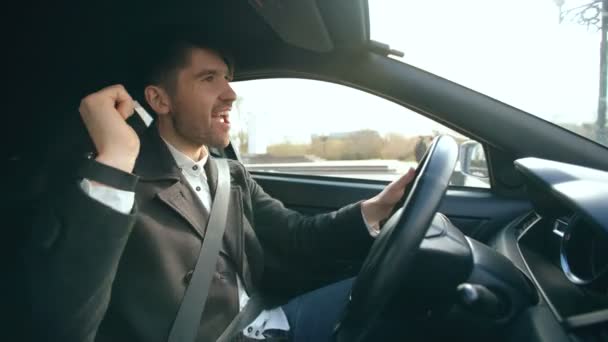 Счастливый красивый бизнесмен водит машину и поет. Человек счастлив, когда заключает сделки и едет домой — стоковое видео
