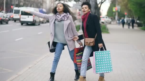 Dvě atraktivní afroamerické ženy s nákupní tašky volá taxi cab při návratu z Obchoďáku prodeje