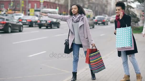 Deux jolies femmes afro-américaines avec des sacs à provisions appelant à taxi tout en revenant de la vente de centres commerciaux — Video