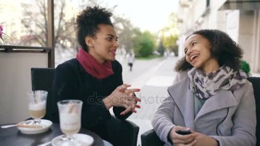 İki çekici konuşan ve içme kahve sokak Cafe yarış bayanlar karışık. Arkadaşlar alışveriş merkezi satış ziyaret ettikten sonra iyi eğlenceler