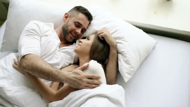 Joven pareja hermosa y cariñosa hablar y abrazo en la cama mientras se despierta por la mañana. Top vista de atractivo hombre charlando su sonriente esposa — Vídeos de Stock