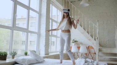 Mutlu gülümseyen genç kadın evde yatakta 360 Vr kulaklık gözlük sanal gerçekliğin kullanırken en iyi deneyimleri elde ederken dans