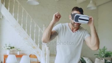 Neşeli genç adam var eğlenceli ve dans 360 Vr kulaklık gözlük sanal gerçekliğin evde yatak odasında kullanırken en iyi deneyimleri elde ederken