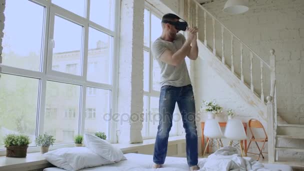 Χαρούμενος νεαρός άνδρας που χορεύει παίρνοντας εμπειρία χρησιμοποιώντας 360 Vr ακουστικά γυαλιά εικονικής πραγματικότητας στο κρεβάτι στο σπίτι — Αρχείο Βίντεο