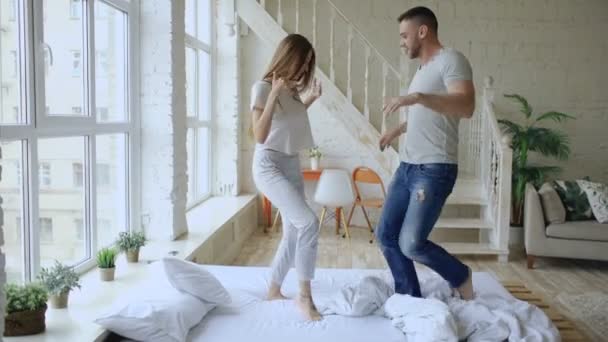 Молодая красивая и любящая пара танцует рок-н-ролл на кровати утром дома — стоковое видео