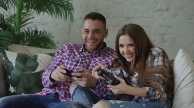 Mutlu ve sevgi dolu bir genç çift gamepad konsol oyun ve eğlenceli evde oturma odasında kanepede oturan
