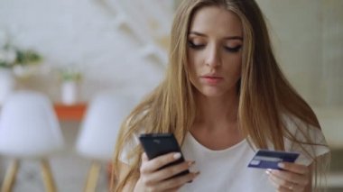 Güzel genç kadın var online bankacılık ve alışveriş evde smartphone ve kredi kartı kullanarak