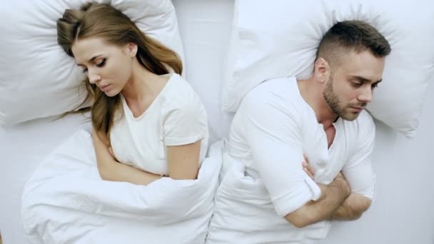 Молодая расстроенная пара, лежащая в постели, испытывает проблемы после ссоры и злит друг друга дома — стоковое видео
