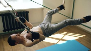 Fitness ekipmanları ve onun kollar ve bacaklar ile çekme parçaIara exircise yapan genç erkek ipleri