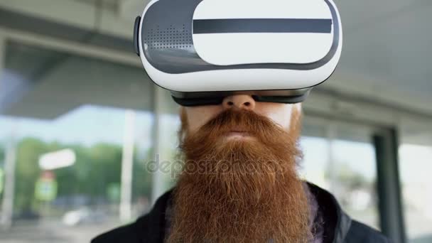Close up of Young bearded man using virtual reality headset for 360 VR experience and take of glasses smiling outdoors — стоковое видео