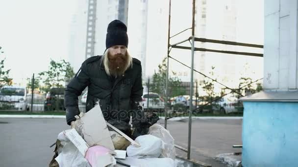 Dolly skott av skäggiga hemlös man gick på gatan med shooping kort på kall höstdag — Stockvideo