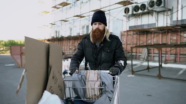 Доллі постріл бородатий бездомний чоловік йшов по вулиці shooping карткою в холодну осінньому дні — стокове відео