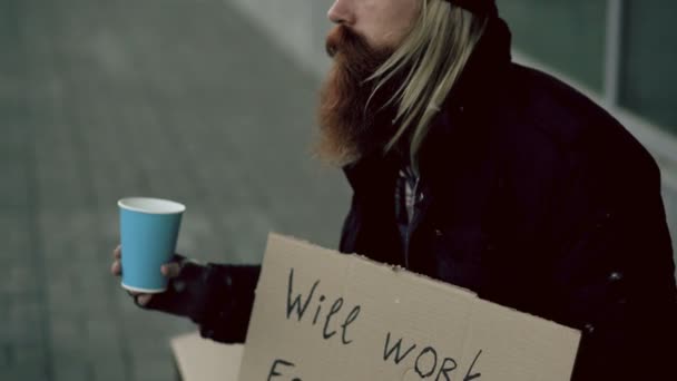 Closeup evsiz genç adam şehir kaldırım, dilenci yakınındaki ilgi insanlar ödemek için Kupası sallayarak para için dilenmek — Stok video