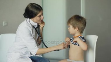 Genç kadın doktor stetoskop tıbbi ofis içinde küçük çocuk dinlerken