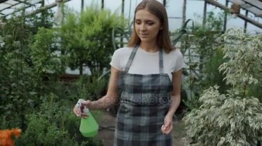 Dolly atış önlük sulama bitki ve çiçekler içinde çekici kadın bahçıvan sera bahçe spreyi