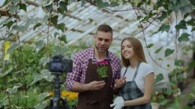 Genç gülümseyen blogger çift bahçıvanlar çiçek söz ve video blog Bahçe hakkında online vlog için kayıt tutarak önlük