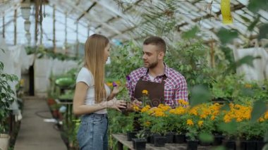Genç neşeli müşteriye söz ve Bahçe merkezinde çalışırken tavsiyede çiçekçi adam