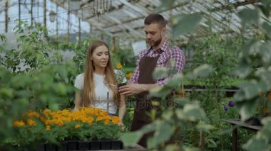 Genç neşeli müşteriye söz ve Bahçe merkezinde çalışırken tavsiyede çiçekçi adam
