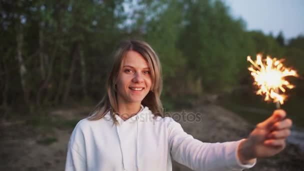 Портрет молодої усміхненої жінки з іскристом святкування на пляжній вечірці — стокове відео
