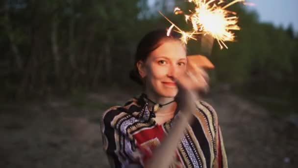 Portret van jonge lachende vrouw met sparkler vieren op beach party — Stockvideo