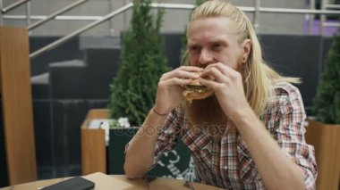Sakallı öğrenci adam yeme hamburger sokak kafe açık havada