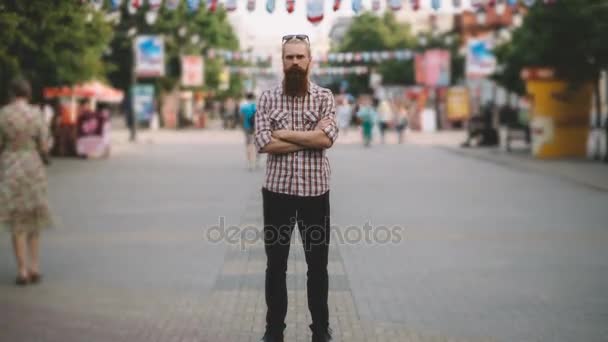 Збільшення часового поясу молодого бородатого чоловіка, який стоїть на тротуарі в натовпі трафіку з людьми, що рухаються швидко — стокове відео