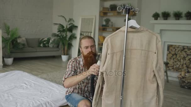 Brodaty mężczyzna parze kurtkę w sypialni w domu — Wideo stockowe