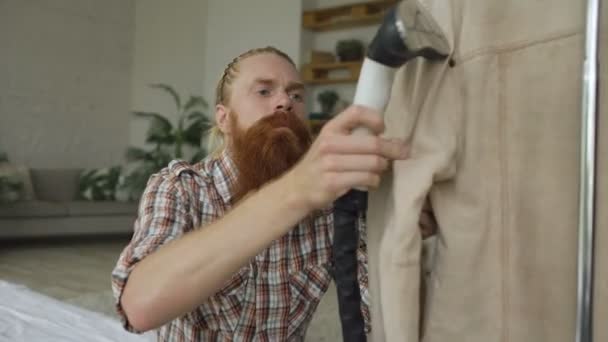 Brodaty mężczyzna parze kurtkę w sypialni w domu — Wideo stockowe