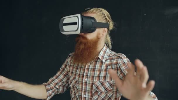 Bearded man wearing virtual reality headset and having 360 VR experience on black background — Stock Video